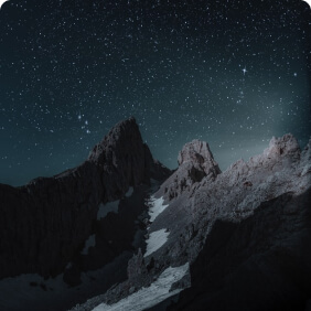 Montanhas rochosas à noite sob céu estrelado.