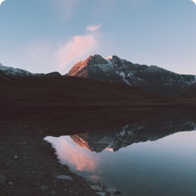 Montanha refletida em lago ao entardecer.
