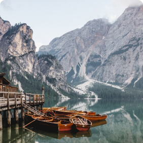 Barcos em lago com montanhas ao fundo.